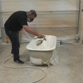 Josh Barnes spraying a refinishing coat on a bathtub
